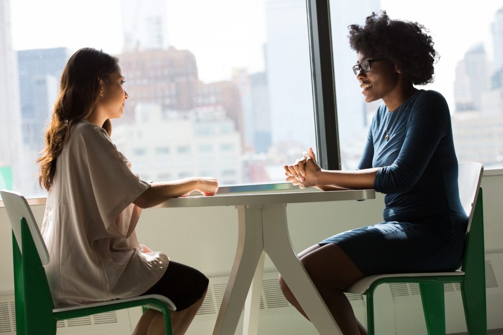 Dos mujeres conversando. Aprende a expresar tus ideas y opiniones de forma clara, respetuosa y efectiva. En este artículo, te explicamos qué es la comunicación asertiva y cómo mejorarla.